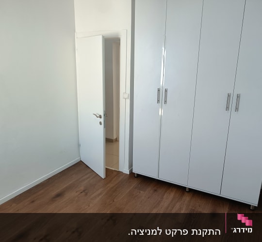 רצפת פרקט עץ חום בחדר ריק עם ארון לבן